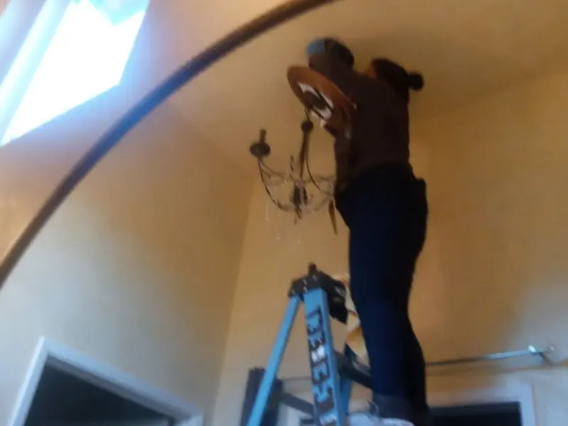 Electrician installing a chandelier in a La Grande residence